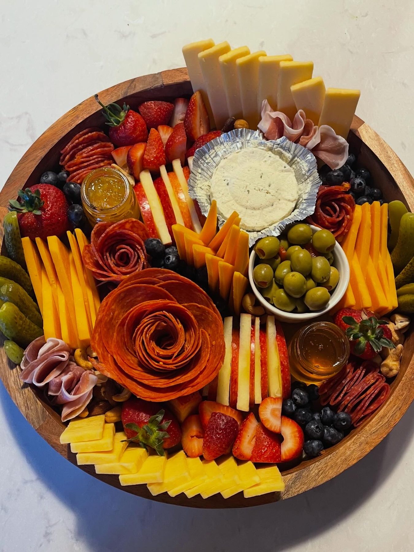 Round charcuterie board with salami roses