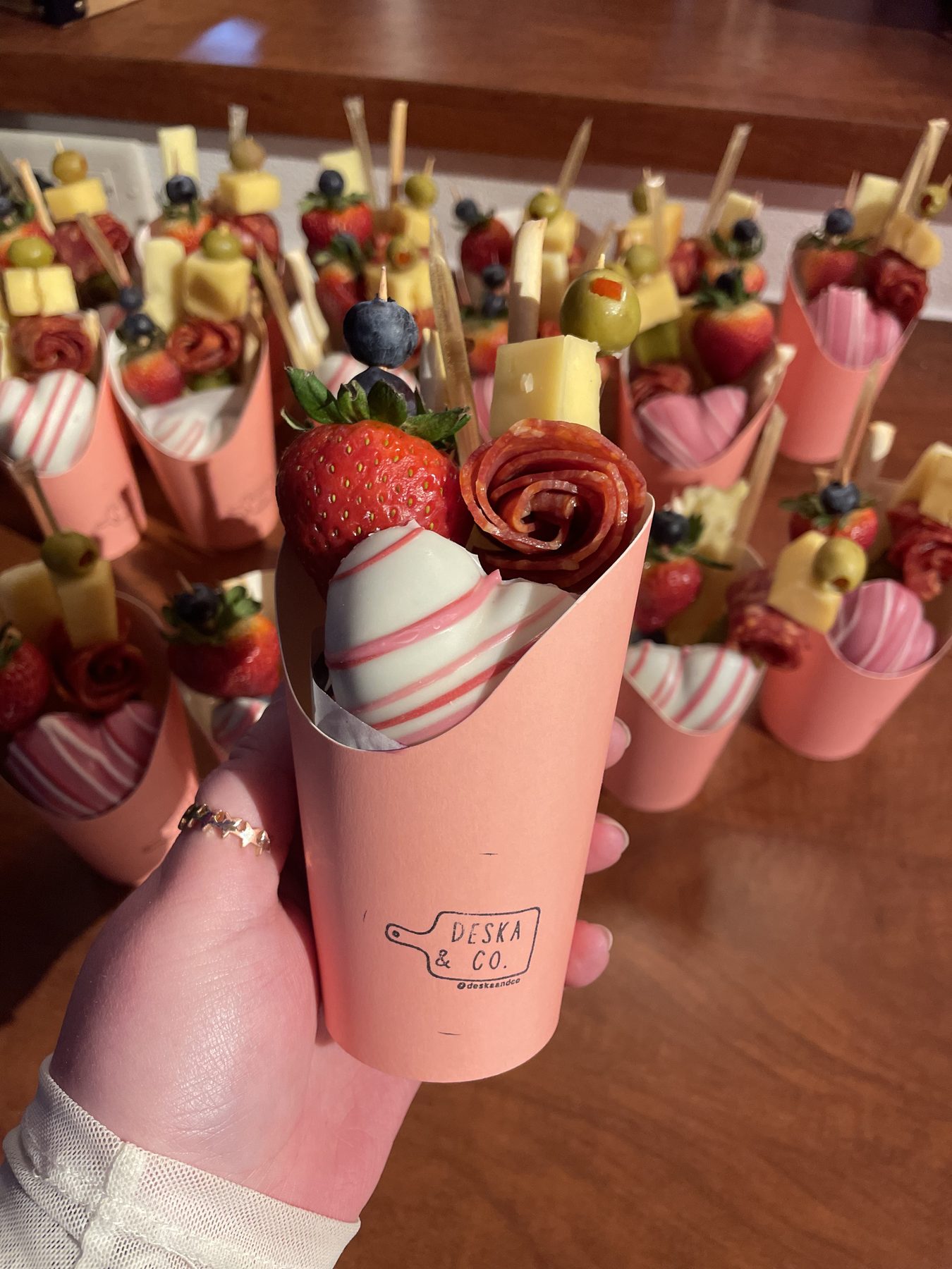A hand holding a charcuterie cup